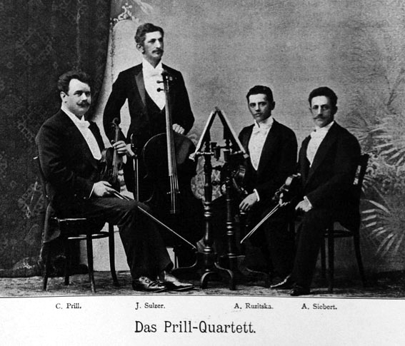 Black and white photograph of the Prill Quartet, three members seated, the cellist standing